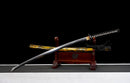 Katana Kohaku — Tamahagane, Poignée noire sur raie blanche, fourreau doré marbré, cordon noir.