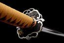 Katana Mikazuki — Acier Damascus, Poignée orange clair, ito noir, garde dorée ajourée, fourreau noir brillant.